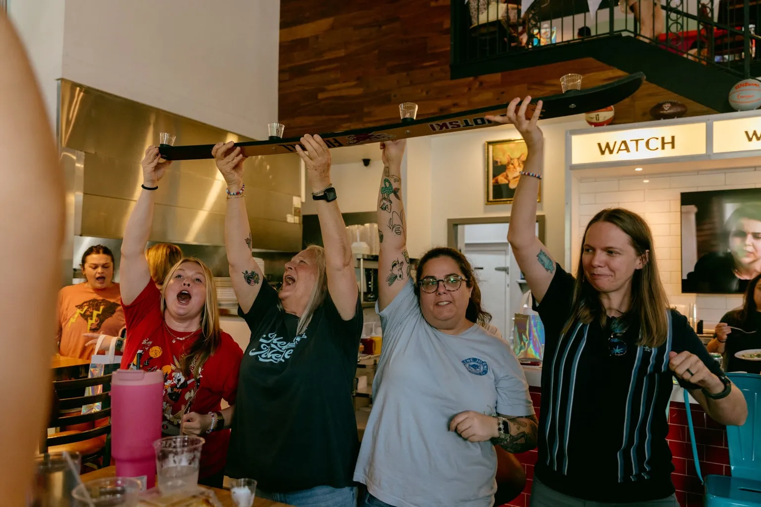 Fans at Jolene Jolene throwing their arms in the air and cheering at a screen