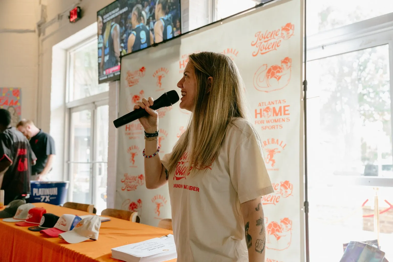 Chelsea Fishman speaking into a microphone at a Jolene Jolene event in front of a branded backdrop