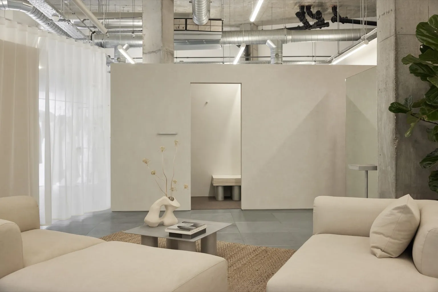 The appointment lounge at The Fall Bride, with cream sofas, a sheer curtain and a sculptural vase