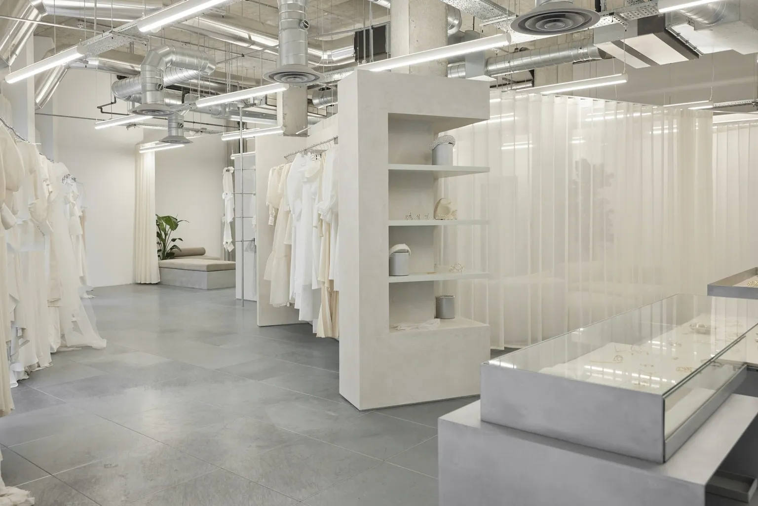 The Brooklyn store at The Fall Bride, with gowns along the walls, a plaster shelving column and a glass jewellery counter