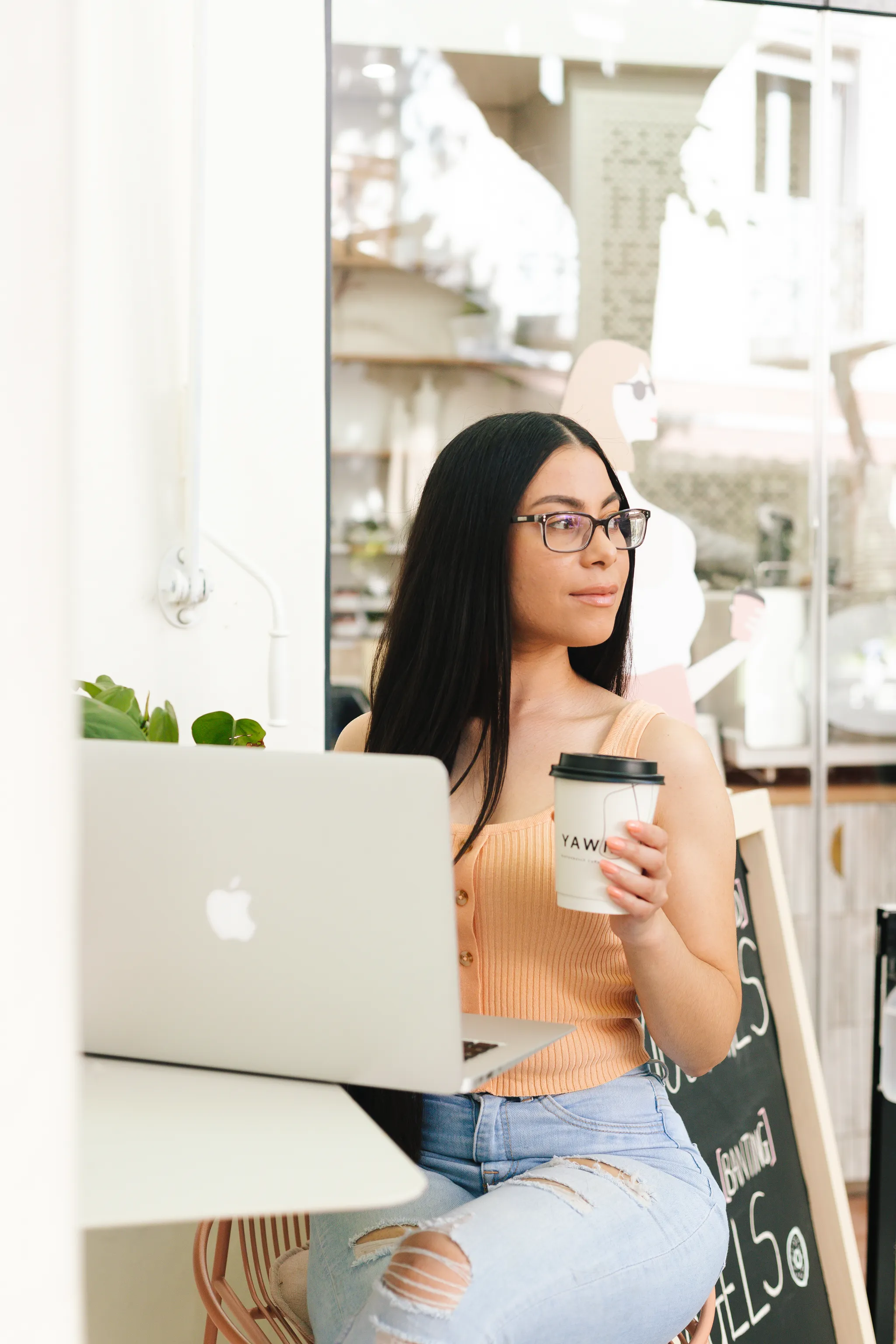 Kamara from The Glow Up Marketing working from a cafe with a laptop and coffee