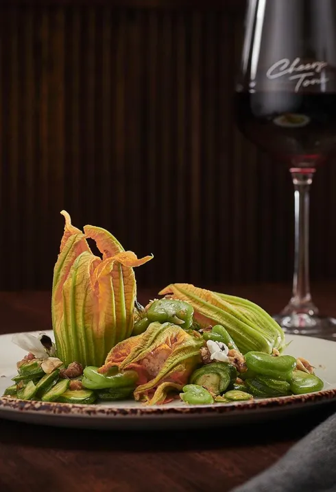 Plated zucchini flower dish with a glass of red wine, photographed by Guy Davies