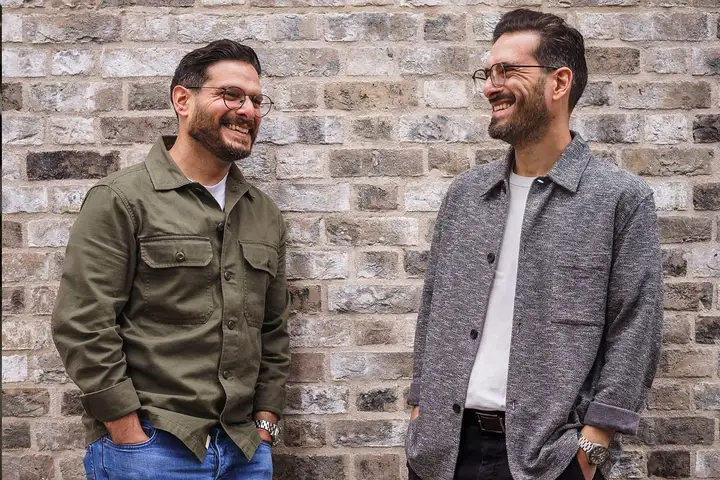 Tarik and Hax, the brothers behind Oh Brother, laughing together against a brick wall
