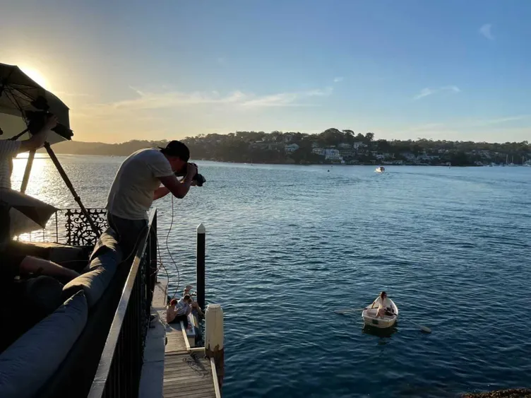 Guy Davies photographing a boat from a waterfront balcony at sunset