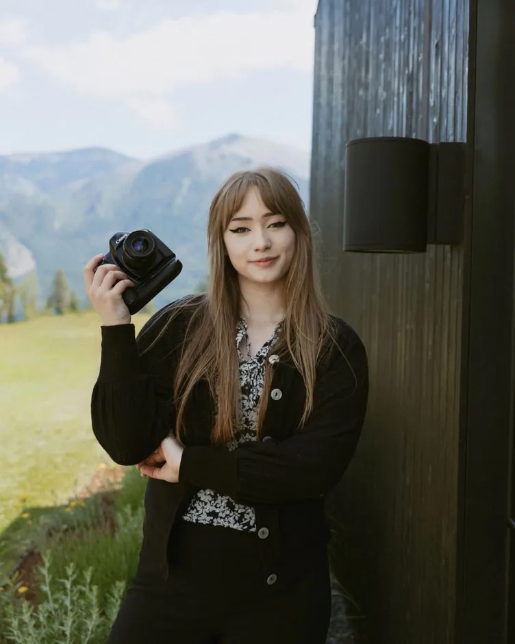 Karmen Trebolo holding a Canon camera over her shoulder in front of mountains