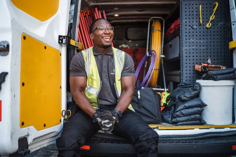 Smiling engineer sitting in the back of a fully racked work van