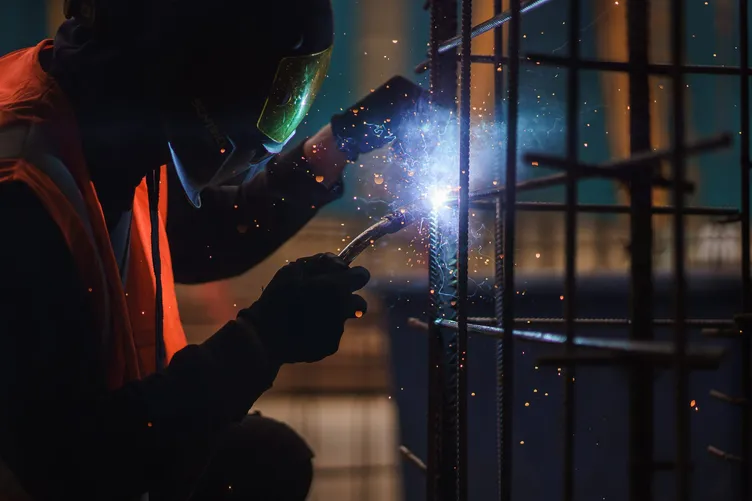 Welder working on steel reinforcement in a shower of sparks
