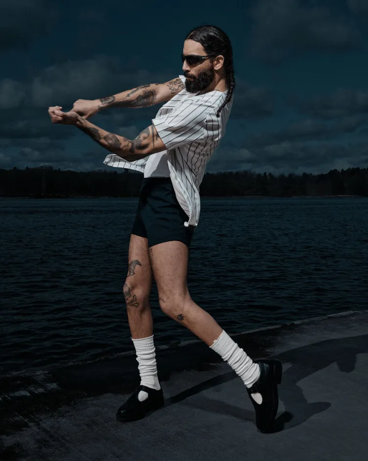 Model in a white pinstripe shirt wearing slouched white SOCKSSS socks on a waterfront pier