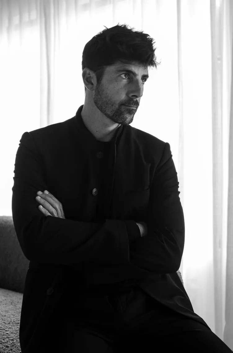 Black and white portrait of Léo Terrando seated in front of sheer curtains