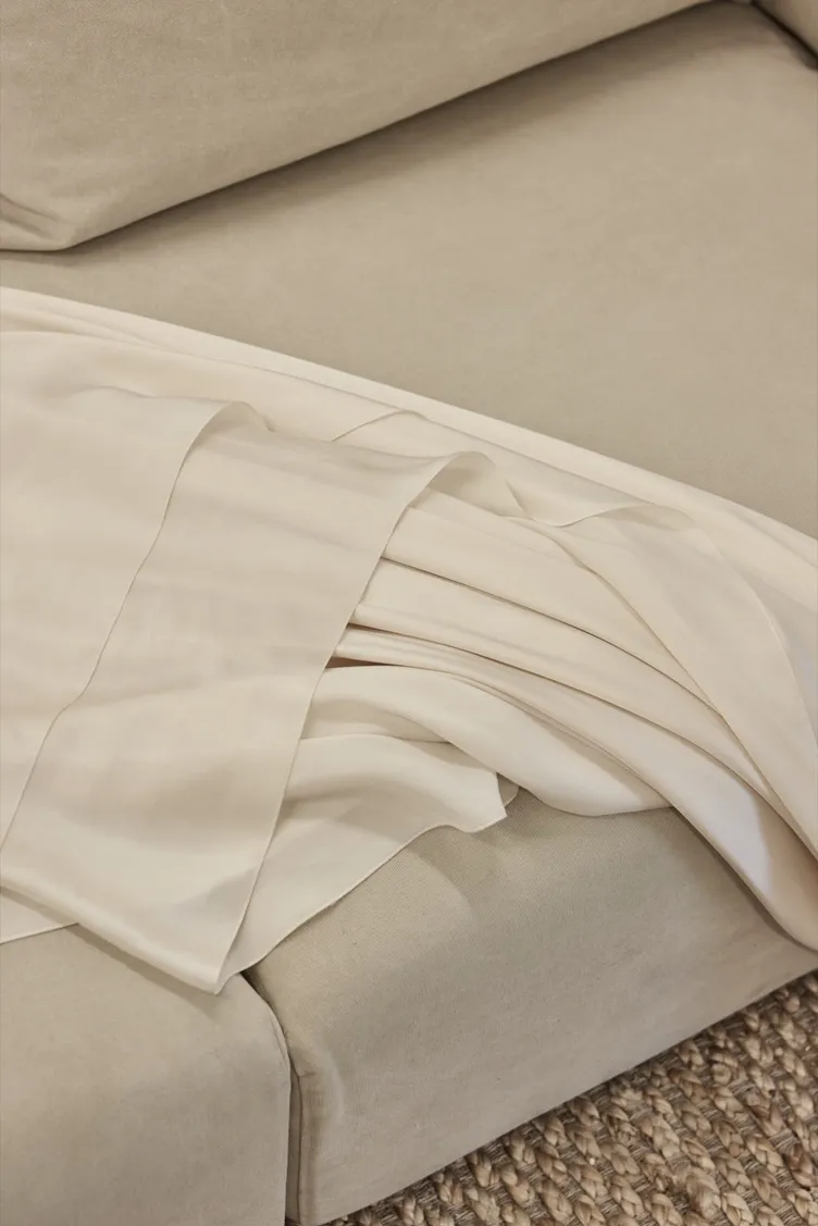 Layers of ivory gown fabric draped over a soft linen sofa at The Fall Bride